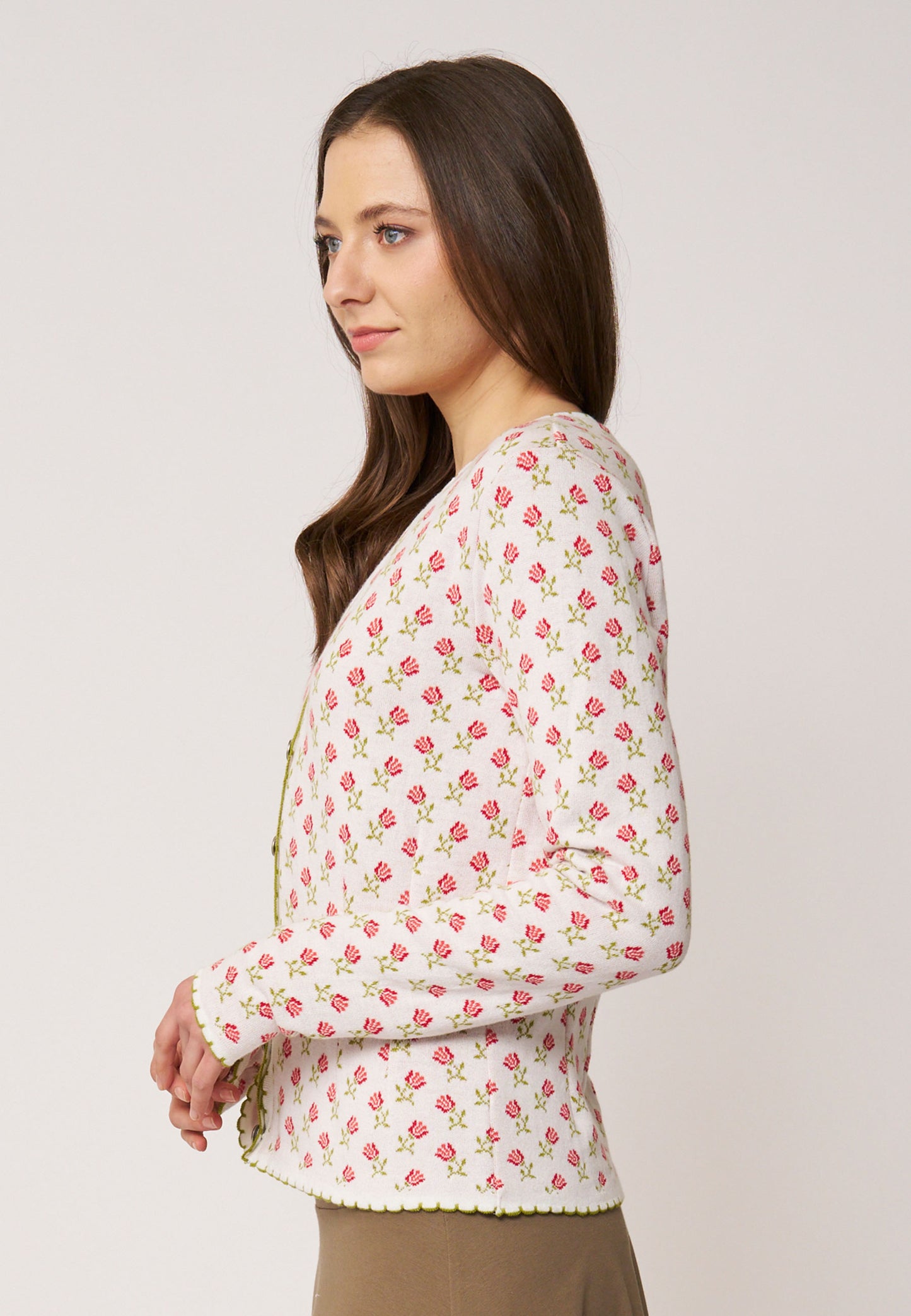 Frau trägt Strickjacke, Modell Lucien, in Ecru mit kleinem rosa Blumenmuster und grünem Zierabschluss, Seitenansicht