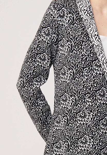 Strickjacke, Modell Jolina lang in schwarz und ecru mit floralem Muster, seitliche Nahaufnahme am Ärmel getragen
