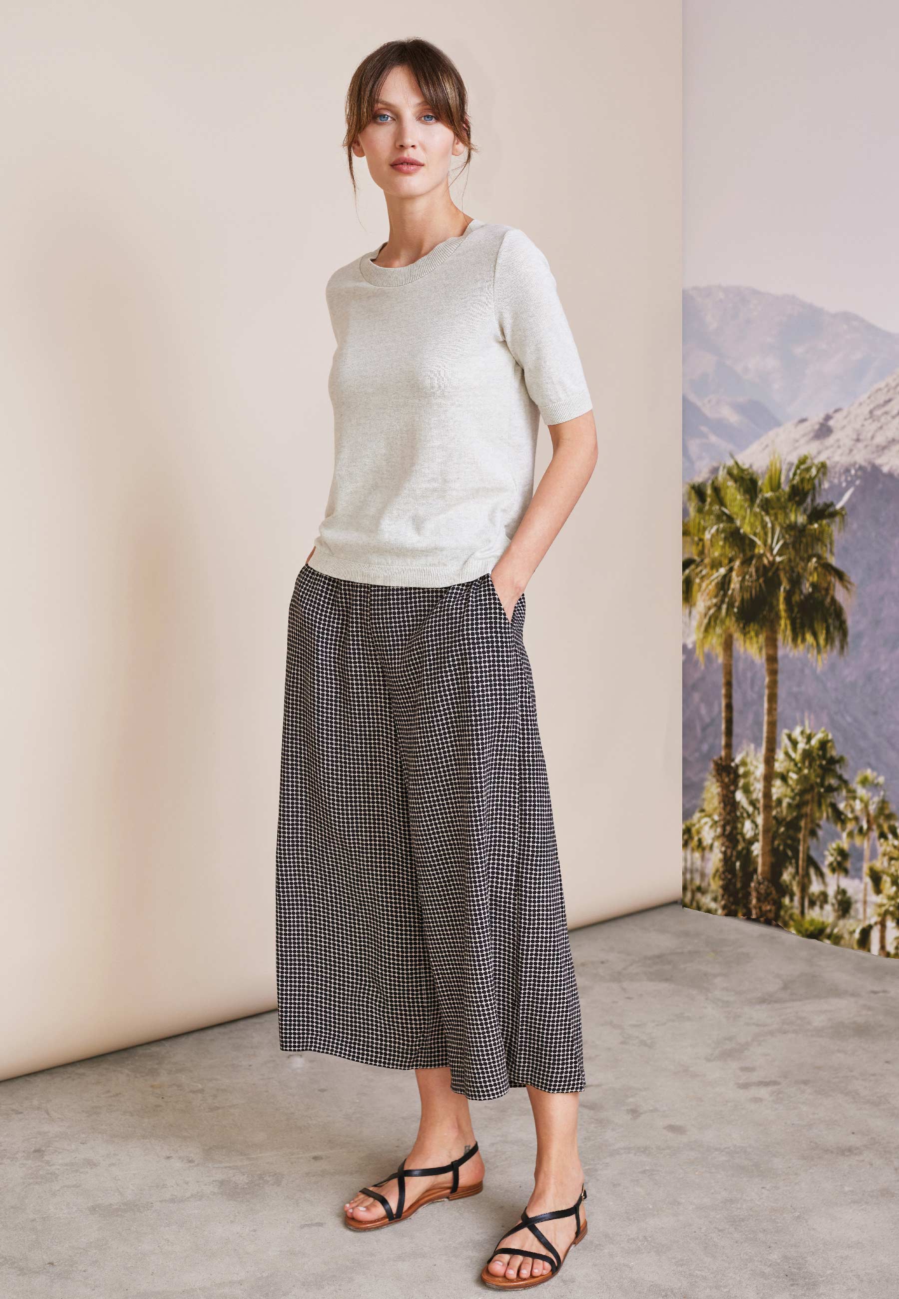 Frau trägt lockere Hose, Modell Helena, mit kariertem Muster in Schwarzweiß, kombiniert mit cremefarbenem kurzärmligen Oberteil