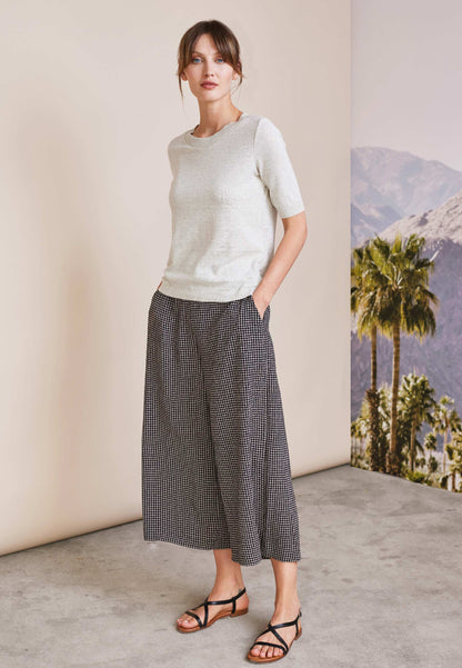 Frau trägt lockere Hose, Modell Helena, mit kariertem Muster in Schwarzweiß, kombiniert mit cremefarbenem kurzärmligen Oberteil
