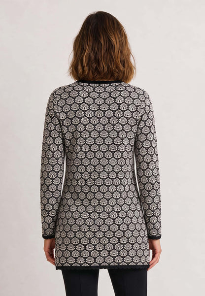 Frau trägt Jacke Eva, Modell lang mit floralem Muster und langen Ärmeln zu schwarzer Hose, Rückansicht