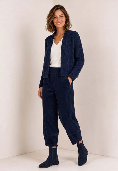 Frau trägt dunkelblaue Jacke, Modell Mitika, mit weißem Shirt, passender Hose und schwarzen Stiefeln