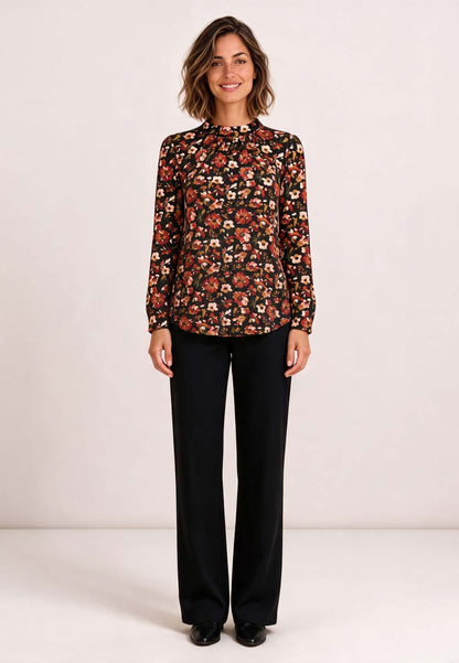 Shirt, Modell Holly mit Blumenmuster an lächelnder Frau und schwarzer Hose vor hellem Hintergrund