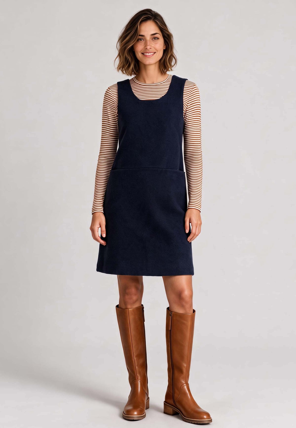 Trägerkleid, Modell Liza in Dunkelblau über gestreiftem Langarmshirt mit braunen Stiefeln