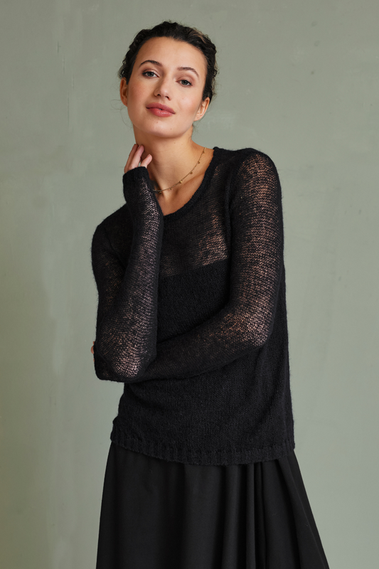 Frau trägt schwarzen, leicht transparenten Pullover, Pulli, Modell Victoria, vor schlichtem, grauem Hintergrund